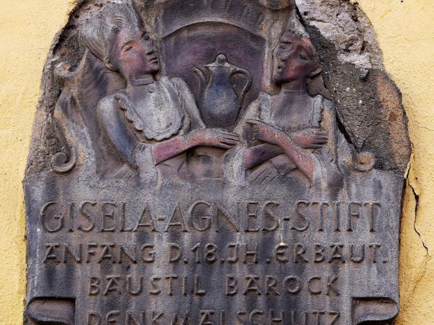 Figürlich gestaltete Denkmalschutz-Plakette am Gisela-Agnes-Stift